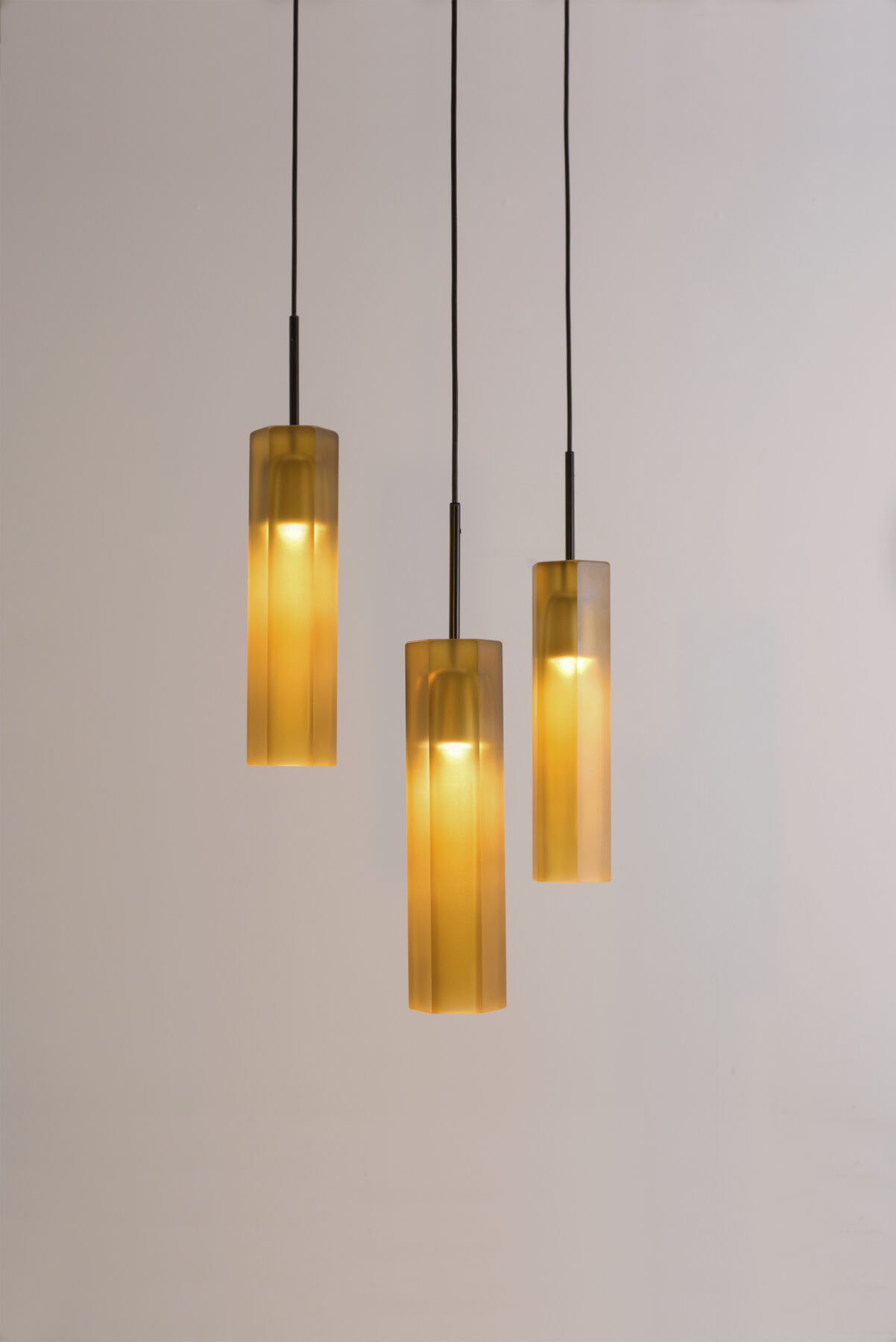 HON pendant lamps made of honey-colored glass with a black cable.