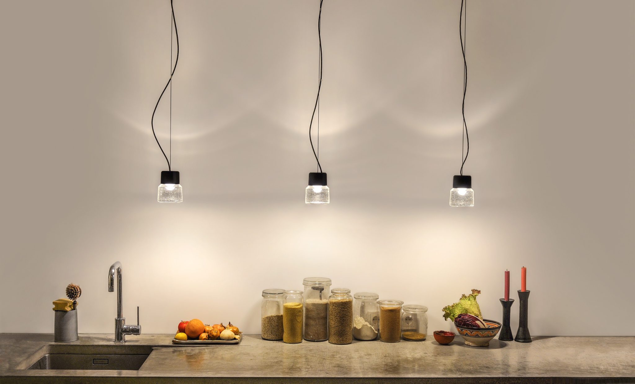 Cast LED pendant luminaire in cast glass and anodised aluminium in a group above the kitchen worktop.