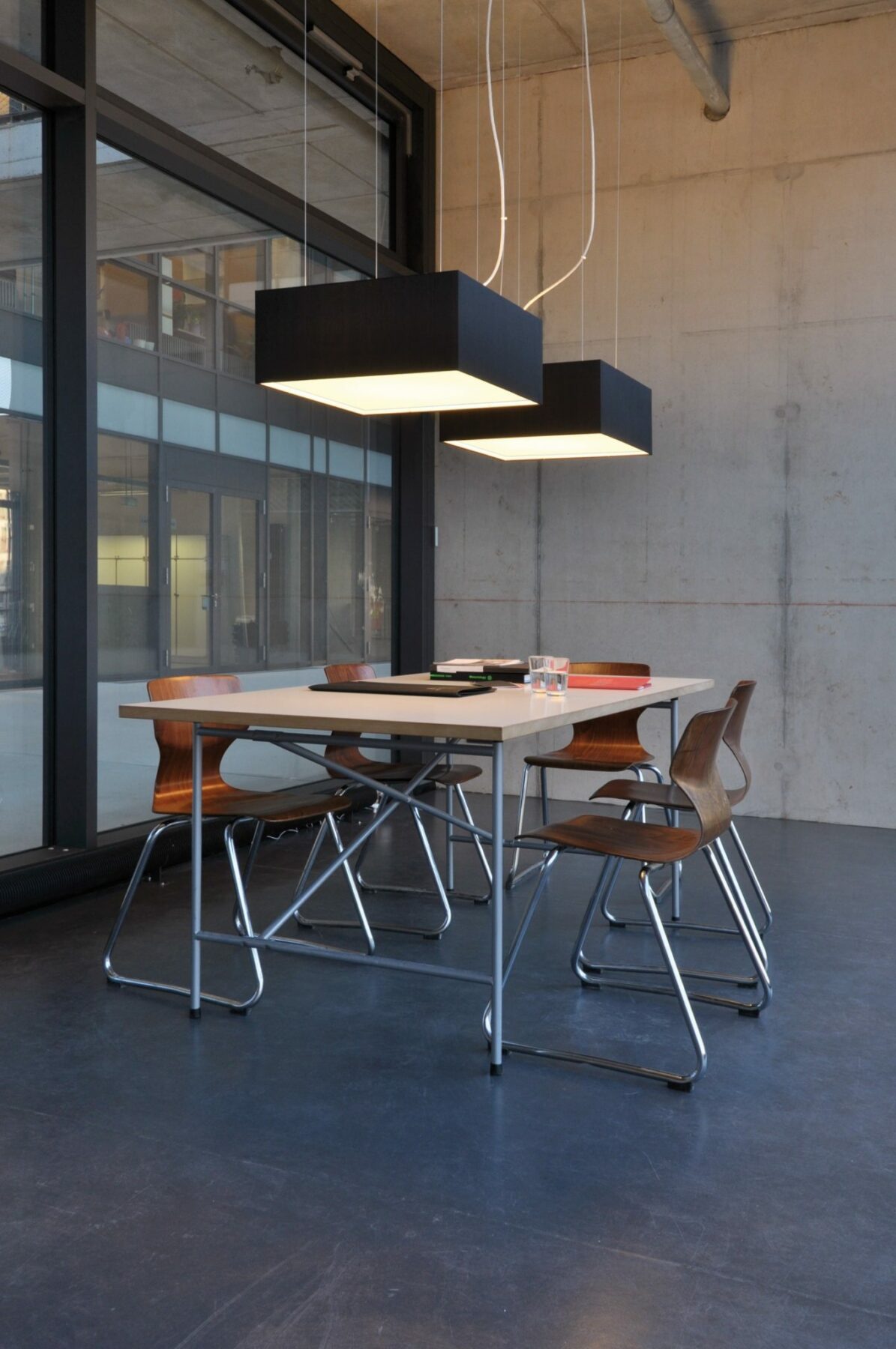 CUBIC FRAME pendant lights in black silk above a table in the creative studio.