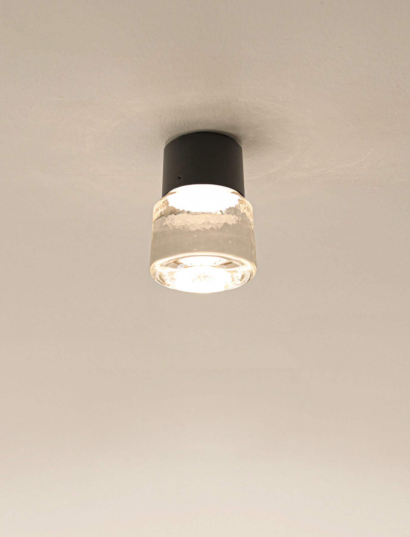 Cast LED ceiling light made of cast glass and black anodised aluminium.