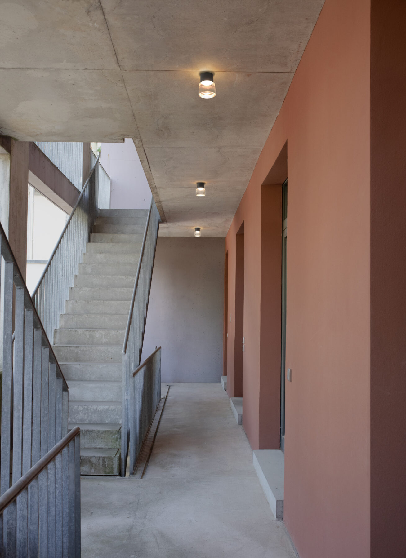 The handcrafted cast glass luminaire CAST M with black aluminum body as outdoor lighting lined up in a modern stairwell.