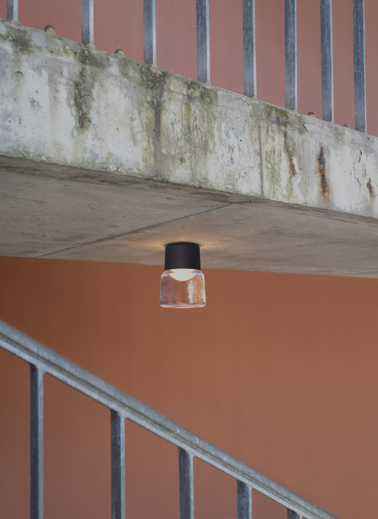 The handmade cast glass luminaire CAST M with black aluminum body as outdoor lighting in modern stairwells.