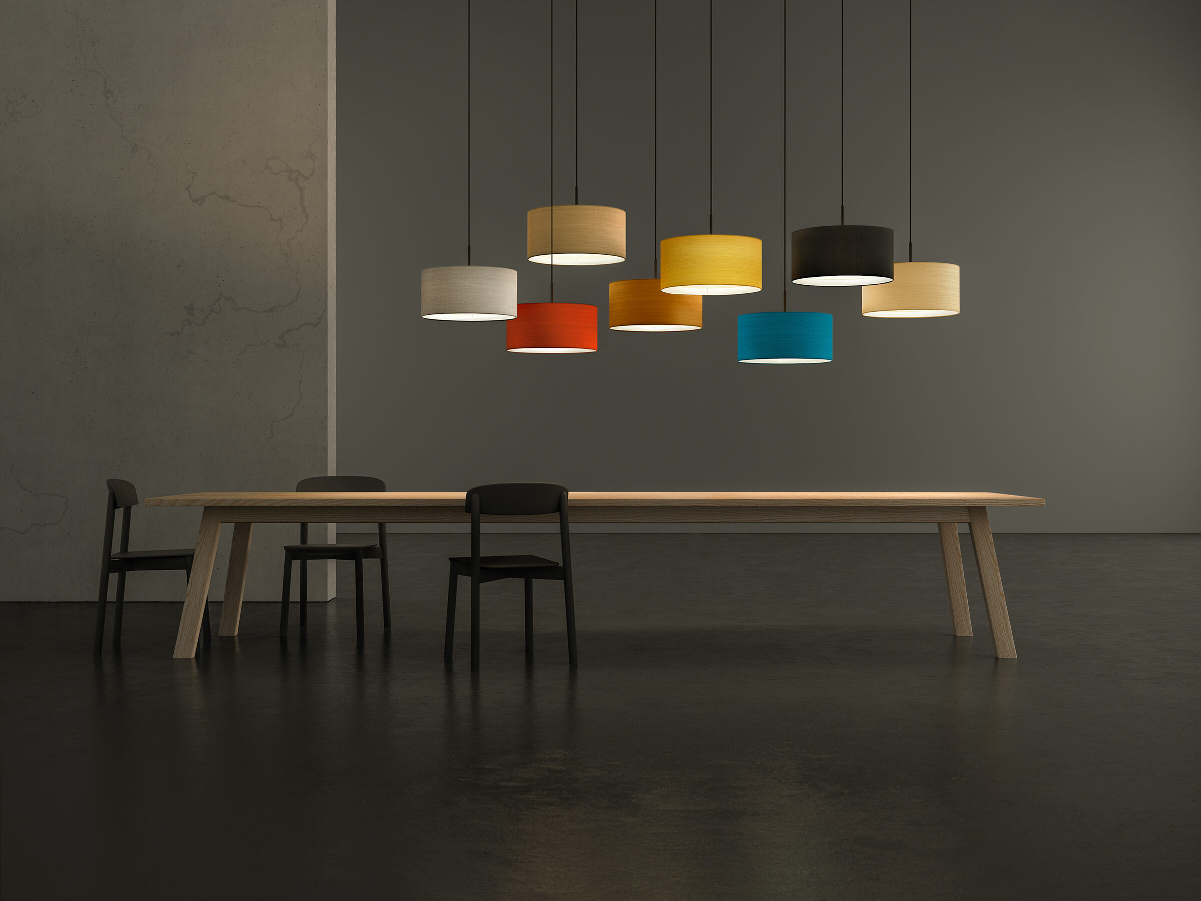 A set of CYLS DRUM pendant lamps in different colours above a large solid wooden table.