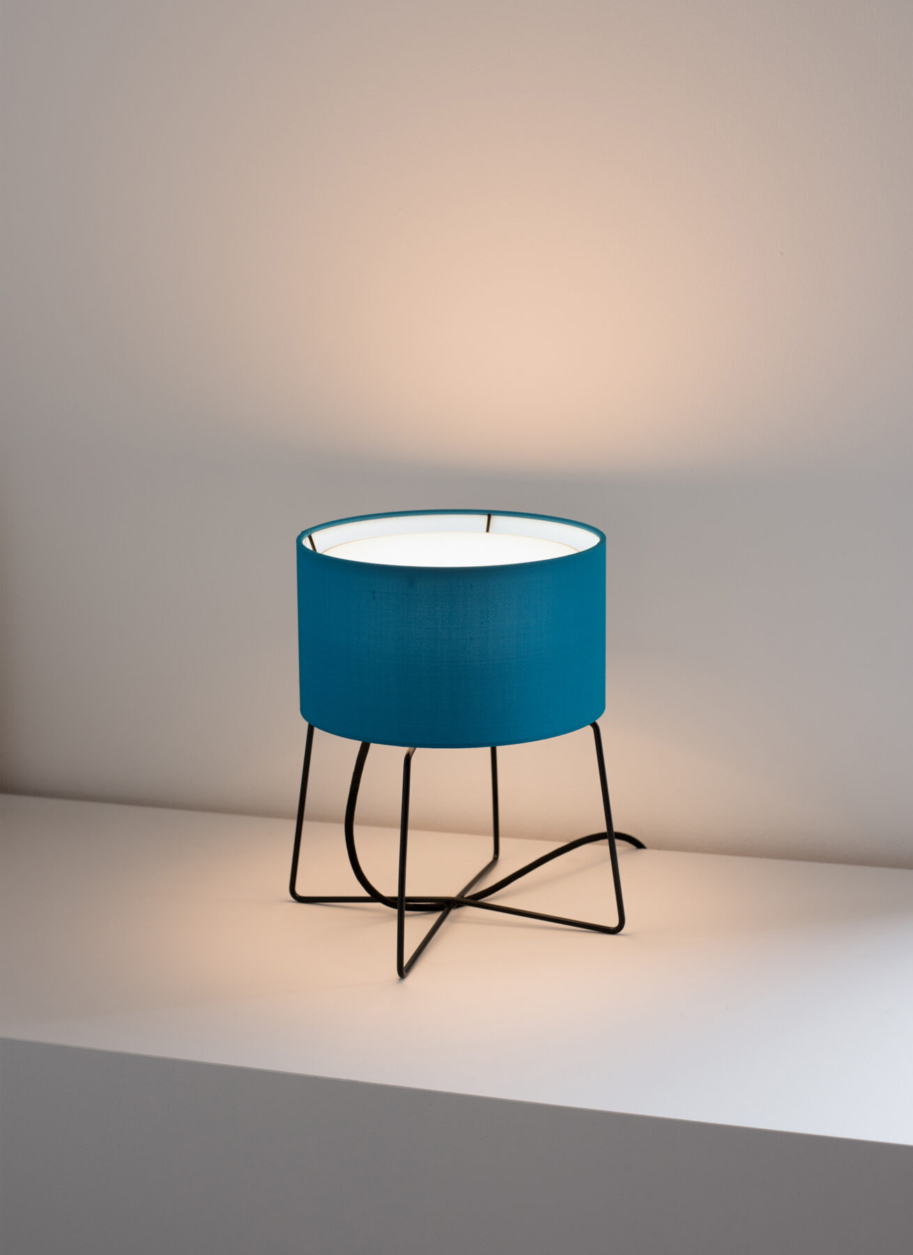 The Orbiter table lamp from filumen with turquoise fabric shade and black base.