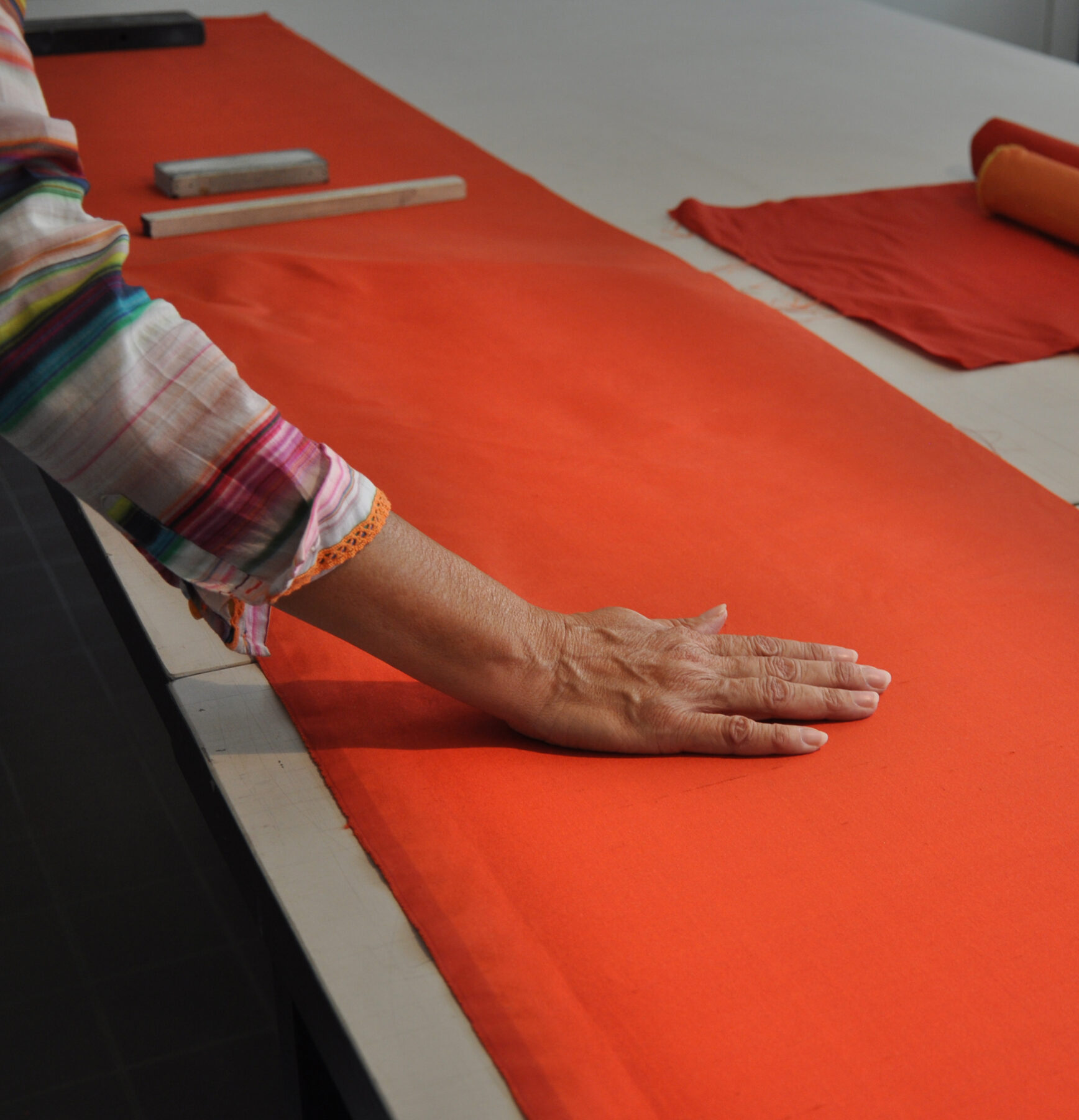 A red dupioni silk is laminated onto the carrier material by hand.