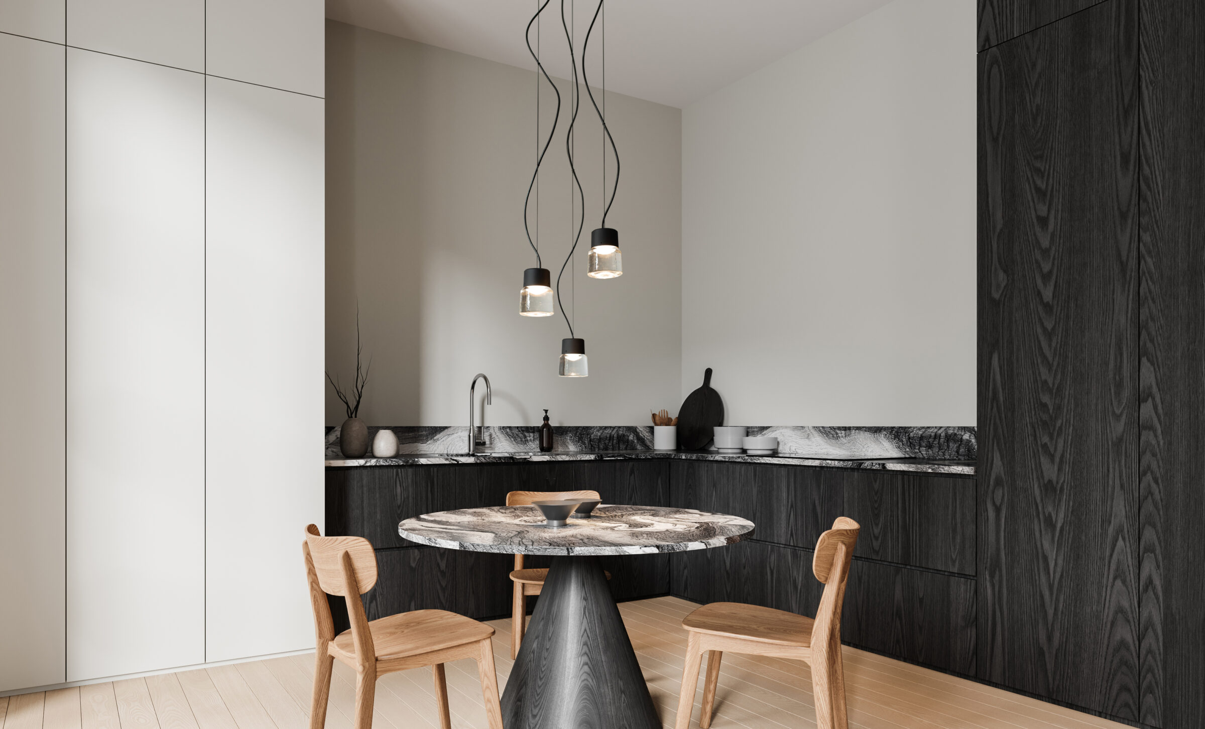 The CAST P pendant light is suspended as a set of three above a stylish round marble table. In the background, a stylish kitchen in black-stained wood and marble.